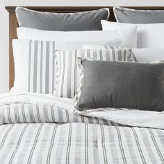 a bed with white and grey striped sheets