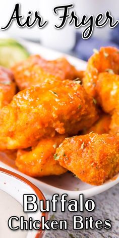 buffalo chicken bites are served on a white plate with sauce and cucumber in the background