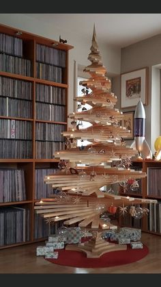 a wooden christmas tree sitting on top of a hard wood floor next to a bookshelf