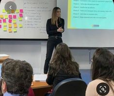 a woman standing in front of a class room full of people