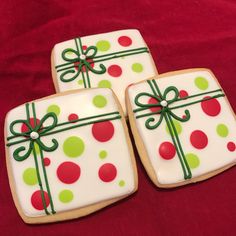 three decorated cookies sitting on top of a red tablecloth covered in green and red polka dots