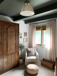 a living room filled with furniture and a large wooden cabinet next to a window covered in curtains