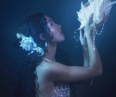 a beautiful woman in a white dress holding a sea shell with pearls on her hands