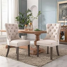 a dining room table with two chairs and a rug on the floor in front of it