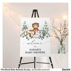 a baby shower sign with a teddy bear on it and lights in the back ground