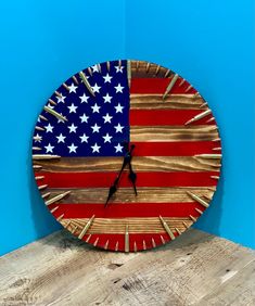 a clock with the american flag painted on it's face, sitting on a wooden table