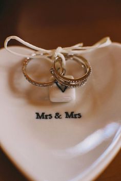 two wedding rings sitting on top of a white heart shaped dish that says mrs and mr