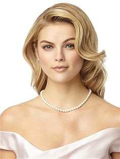 a woman in a white dress wearing a pearl necklace