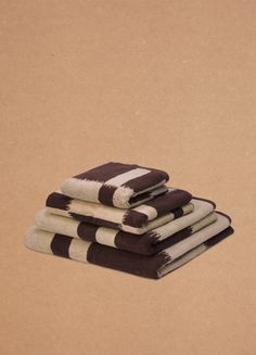 four towels stacked on top of each other in front of a brown background with black and white stripes