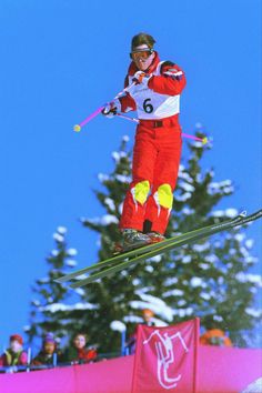 a person on skis jumping in the air with trees in the back ground behind them