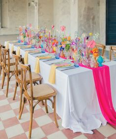 a long table is set up with plates and vases on it for a party