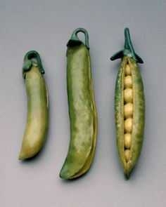 three peas and two peas pods on a gray surface