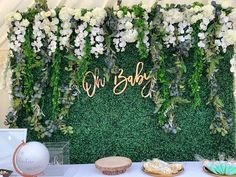 a table topped with lots of white flowers and greenery next to a sign that says no baby