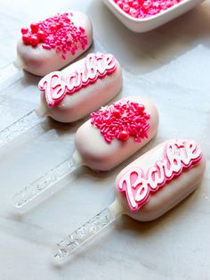 three lollipops with pink sprinkles and the word barbie on them