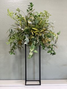 a plant in a black metal vase on a white countertop next to a gray wall