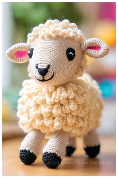 a crocheted sheep sitting on top of a wooden table