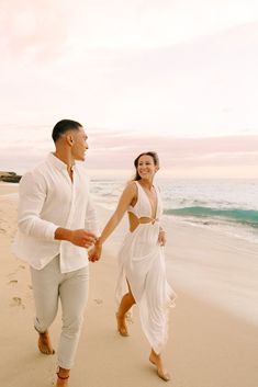 a man and woman walking on the beach holding hands