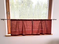 a window with two red curtains hanging from it's side