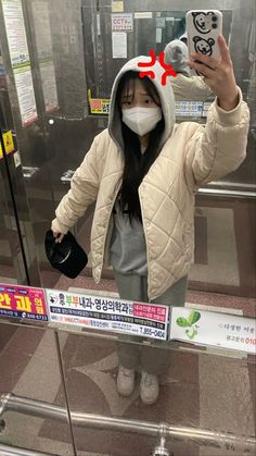 a woman wearing a mask taking a selfie with her cell phone