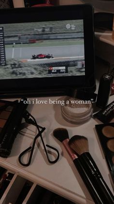 a table topped with cosmetics and makeup brushes next to a tablet computer screen that reads, oh i love being a woman