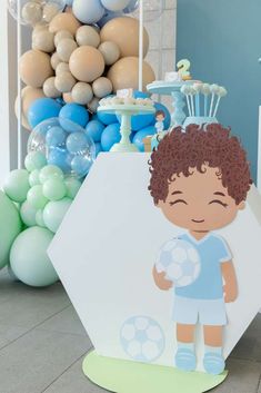 a paper cut out of a boy holding a soccer ball and standing in front of balloons