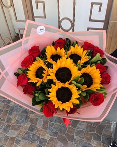 a bouquet of sunflowers and roses in pink paper