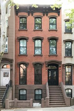 an apartment building with stairs leading up to the front door and second story windows on either side