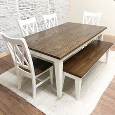 a dining room table and bench in front of a brick wall