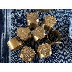 six brass napkin rings on a blue and white rug