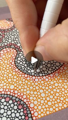 a person using a pen to draw on a piece of paper with circles and dots