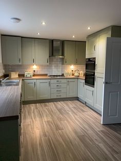 A green shaker kitchen with woodern floor and worktops with stainless steel handles and a pale brown dog Interior Design Kitchen Green, Cranbrook Sage Kitchen, Sage Green Kitchen Inspiration, Small Sage Kitchen, Small Sage Green Kitchen, Green And Wooden Interior, Green And Wooden Kitchen, Shaker Kitchen Green, Green Shaker Style Kitchen