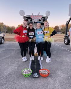 three girls in costumes standing next to some food