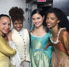 four young women dressed in period costumes posing for the camera with their arms around each other