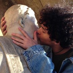 a man is kissing a statue with his hands