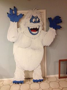 a large white monster standing in front of a door with his hands up and mouth wide open