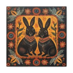 two black rabbits are sitting next to each other in front of an orange and yellow background