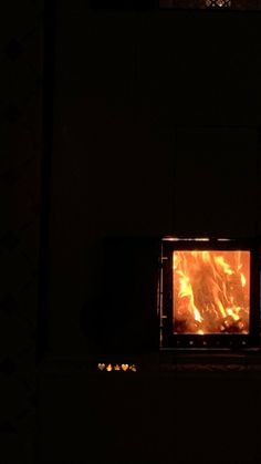 a fire is burning in the fireplace with it's light on and dark background