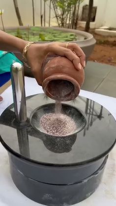 a person pouring something into a bowl on top of a table