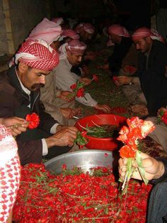 several men in red and white turbans sit around a table full of flowers