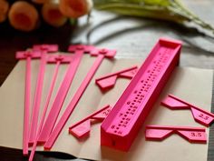 four pink plastic utensils sitting on top of a piece of paper next to radishes