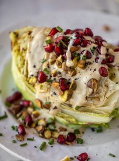 a white plate topped with an artichoke covered in sauce and pomegranates