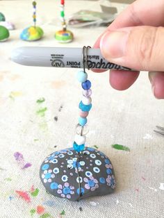 a hand holding a pen over a heart shaped object with beads and beads on it