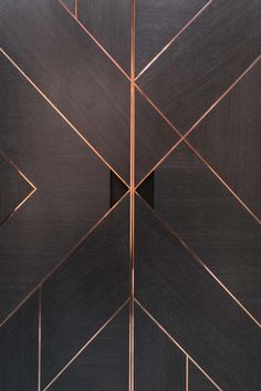 a black and gold tiled wall with an arrow design in the center, as well as lines on it