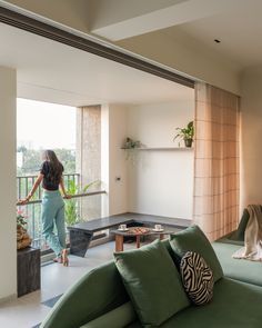 a woman is standing in the living room looking out at the balcony and patio area