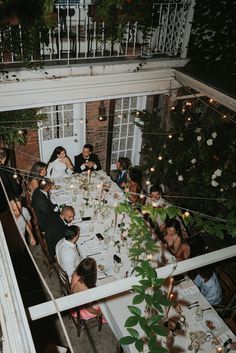 a group of people sitting around a table with white clothed tables and flowers on it