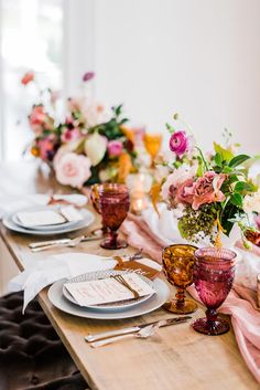 the table is set with place settings and flowers in vases on each one side