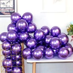 purple balloons stacked on top of each other in front of a metal rack and table