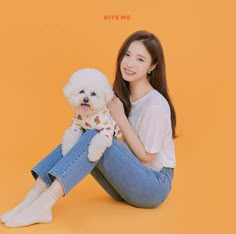 a woman sitting on the ground holding a white dog