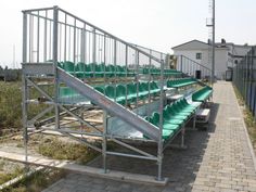 a row of green seats sitting next to each other on top of a brick walkway