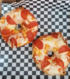 two pepperoni pizzas sitting on top of checkered paper